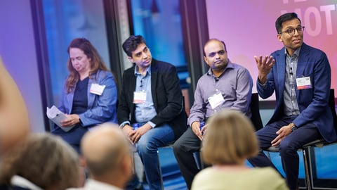 Four people in a panel with the man on the right talking